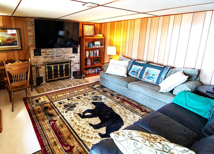 The lower-level family room is a walkout with lake access, a concrete patio, cozy seating, a 65" TV, and a pool table. Savršen za opuštanje, ovaj privlačni prostor nudi udobnost, zabavu i jednostavan pristup na otvorenom kako biste uživali u okruženju uz jezero.