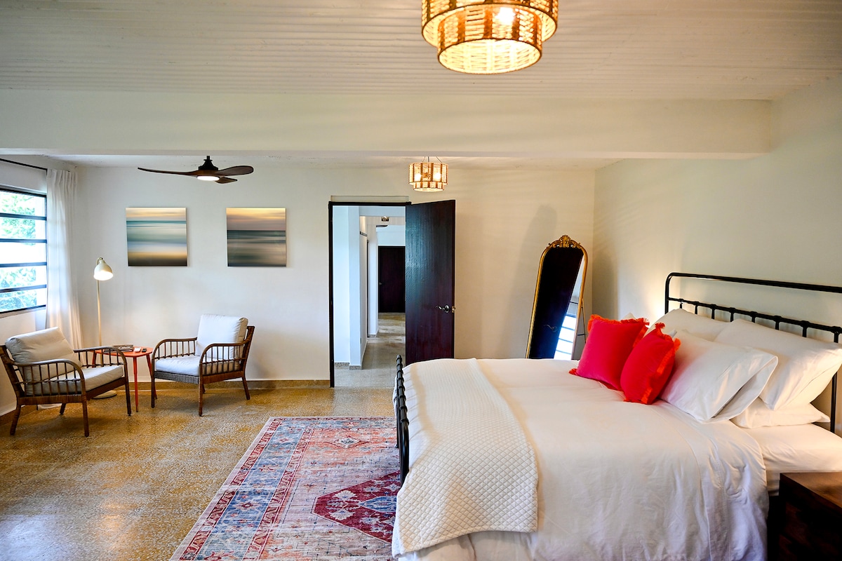 Spacious master bedroom with a king-size memory foam bed, cozy reading corner, vintage mirror, and private mountain view. Designed for comfort, slow living, natural light, and quiet relaxation.