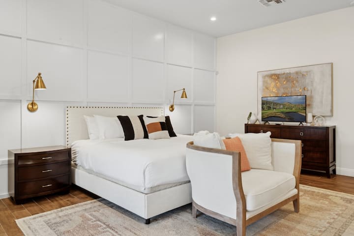 Unwind in this serene master retreat featuring a king bed, chic accent lighting, cozy loveseat, and a large smart TV. The spacious layout and elegant details create the perfect space to relax and recharge in style.