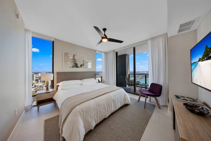 Dormitorio moderno con cama tamaño king, impresionantes vistas a la ciudad y al agua.