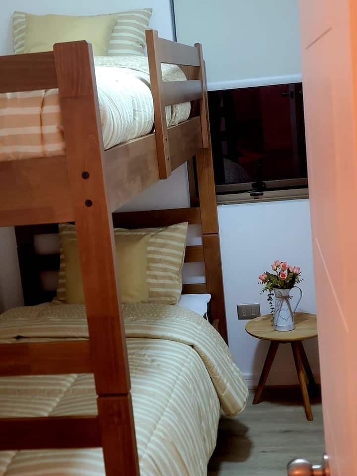 Slaapkamer met houten stapelbed, rolraam en bijzettafel 
Perfect voor kinderen of vrienden: veilig, comfortabel en praktisch, elk met een eigen bed en ruimte om hun spullen achter te laten.