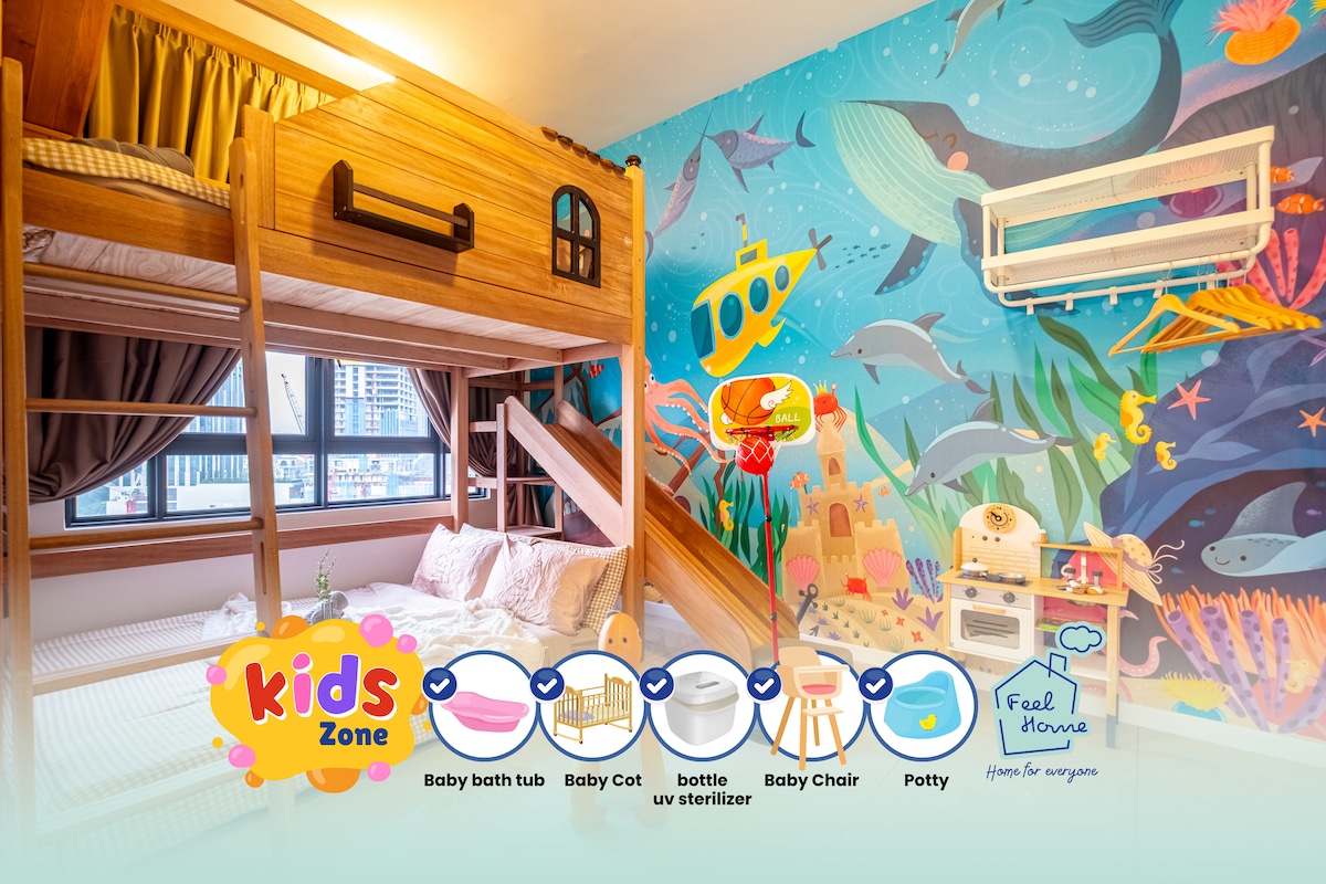 A children's bedroom features a fun bunk bed with a slide, providing an engaging sleeping area. A vibrant underwater mural captures attention, while a play kitchen and baby accessories are visible. A potty and baby chair complete the playful environment, ensuring a comfortable space for kids.