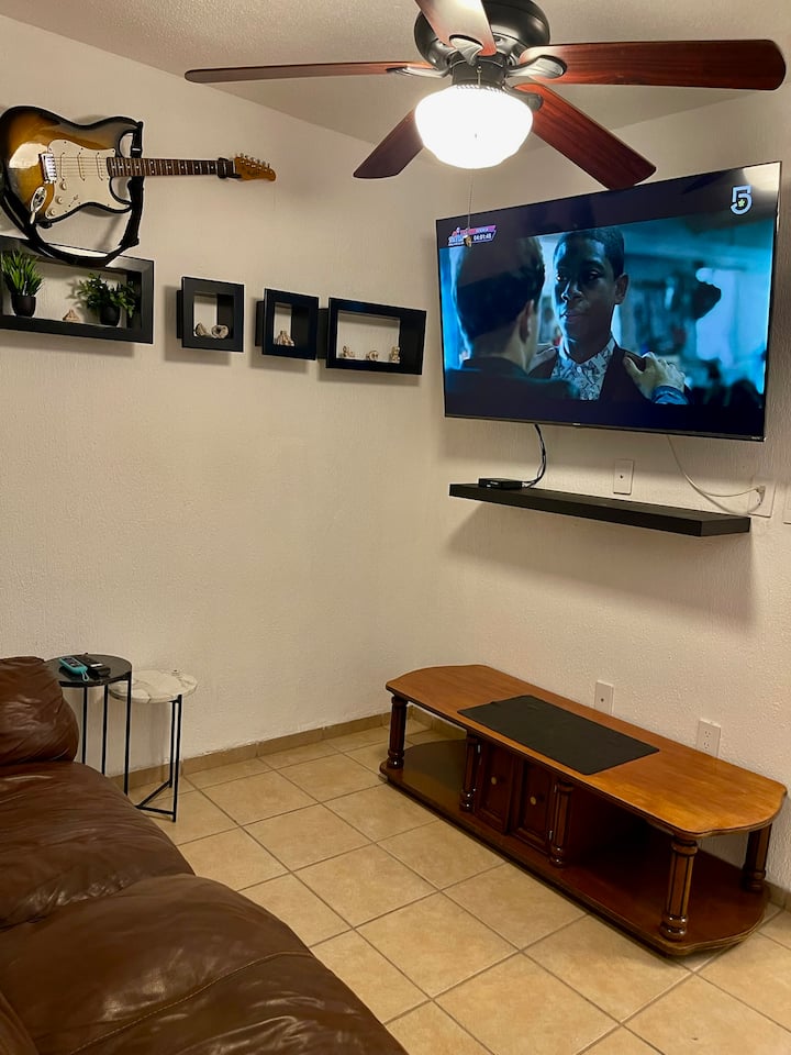 TV soba s SmartTv-om od 58"s kabelskom televizijom, stropnim ventilatorom, 2 mramorna stolića, drvenim središnjim stolom i kožnim kaučem.