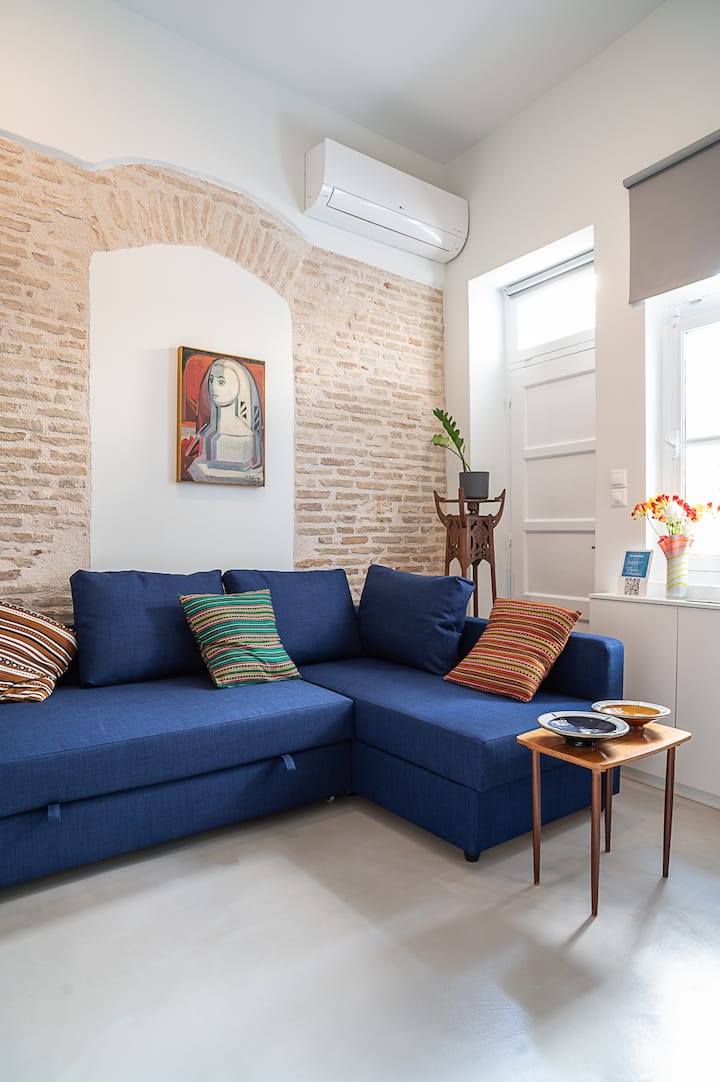 Длабокиот син аголен кауч во вториот стан е удобен кревет со целосна големина, нудејќи дополнителен простор за спиење. Во комбинација со живописни перничиња и поставена на свод од тули, ја спојува практичноста со удобен, модерен шарм.