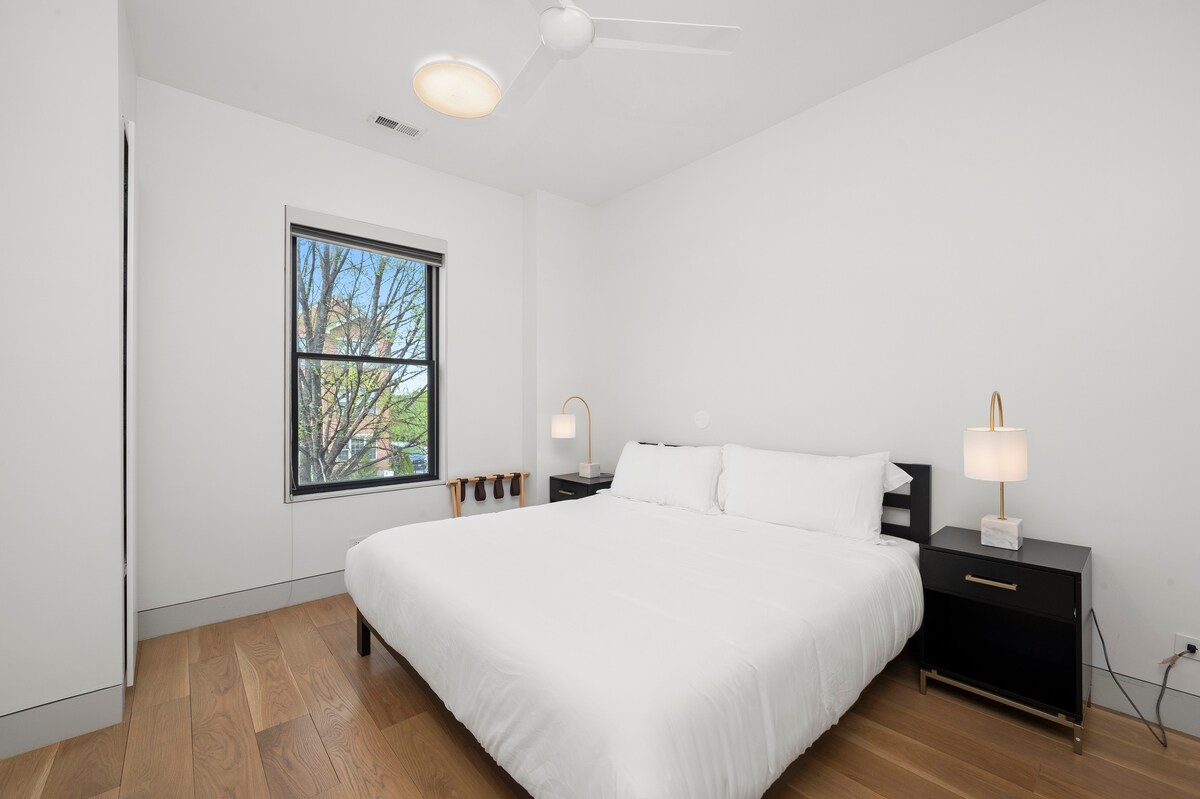 Dormitorio luminoso y acogedor con una cama tamaño king, mesitas de noche negras modernas y pisos de madera cálidos. Este acogedor espacio también incluye un baño privado en suite, ideal para mayor comodidad, comodidad y una estadía tranquila.