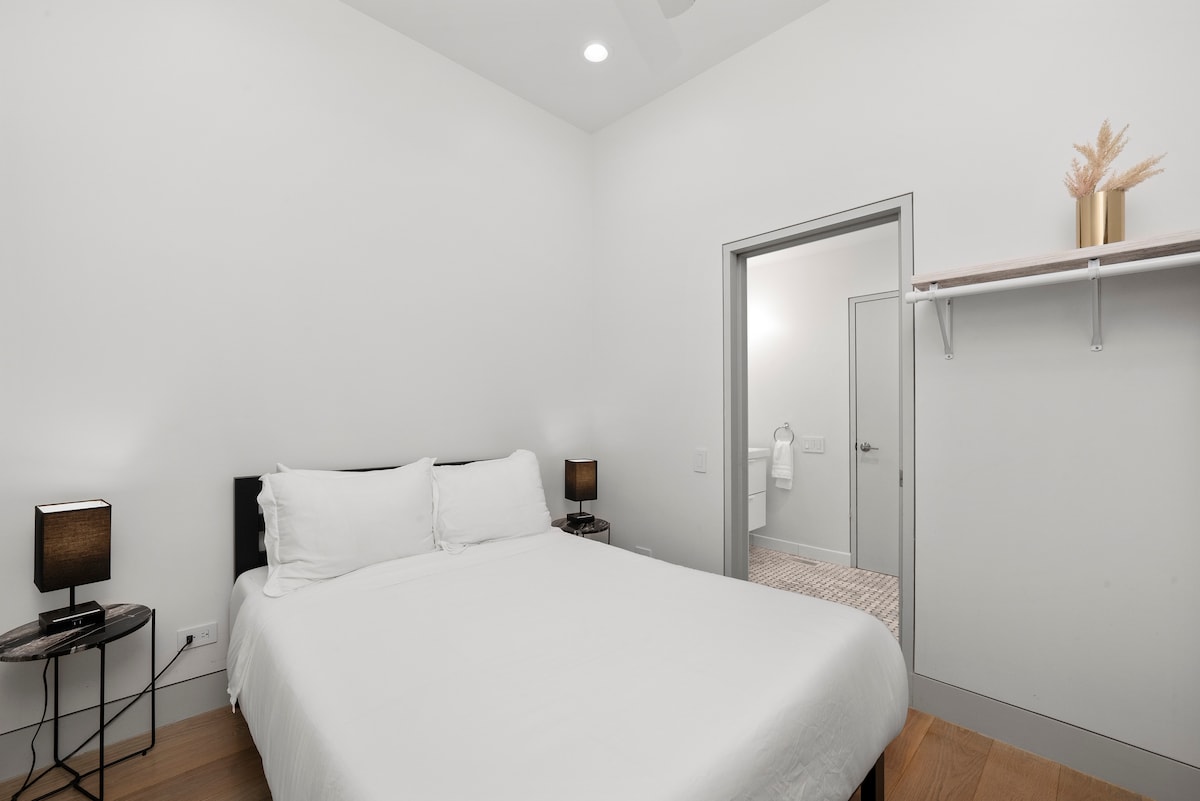 Dormitorio en la planta baja con cama de tamaño completo, iluminación minimalista y un diseño limpio y moderno. Esta habitación incluye un cómodo acceso directo al baño común