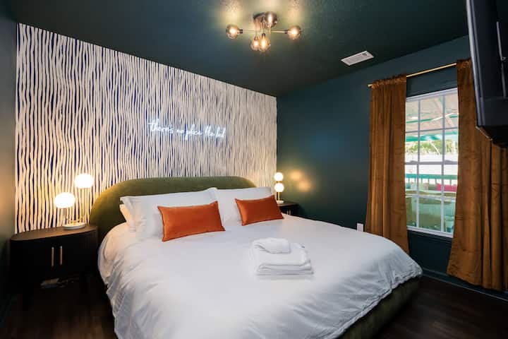 Moody, modern, and made for rest. This king suite features plush bedding, luxe lighting, Smart TV and a neon glow "there's not place like bed" that sets the vibe. Perfect for a cozy night in or a slow morning with sunlight streaming through.