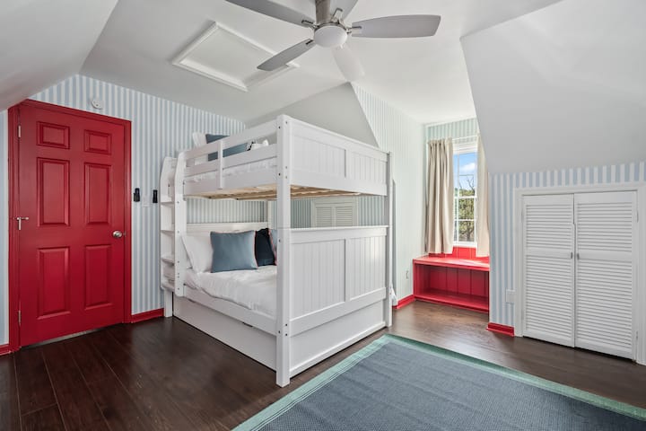 This coastal-inspired room features a full-over-full bunk with a hidden twin trundle, elegant blue-and-white walls, a designer cabana chair, sculptural lamp, and Smart TV. Enjoy stunning sunrise views and dreamy sunset glow from the front window.