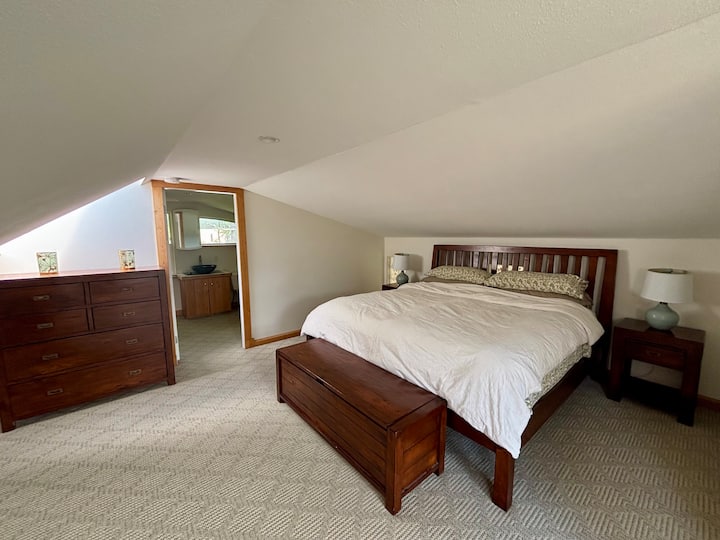 Chambre à l'étage avec lit king size et salle de bain attenante.