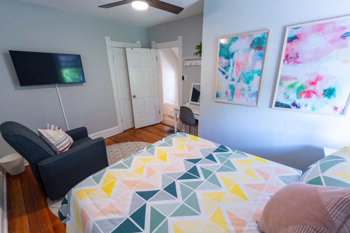 تحتوي غرفة كوين في الطابق الثاني على مصباحين بجانب السرير مع منافذ شحن للإضاءة ومنفذ USB - C مع منفذ قياسي في المصباح. يحتوي على رفوف في الخزانة للملابس والشماعات. يوجد تلفزيون ذكي ومنضدة تزيين ومرآة وكرسي هزاز.