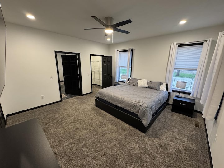 主卧的斜视图，配备 2 米宽双人床。 这张照片展示了通往主卧壁橱、主卫生间、吊扇和灯的门敞开着。