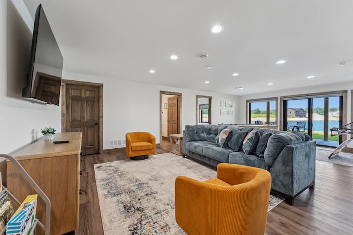 พื้นที่นั่งเล่นชั้นใต้ดินมีโซฟา เก้าอี้ 2 ตัว ทีวีขนาดใหญ่พร้อมบริการสตรีมมิ่งของโรคุ เตาผิงไฟฟ้า เกม และหนังสือ