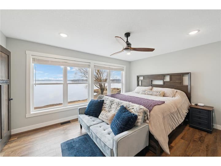 Голяма спалня с двойно легло и достъп до собствена баня с големи прозорци с изглед към езерото.