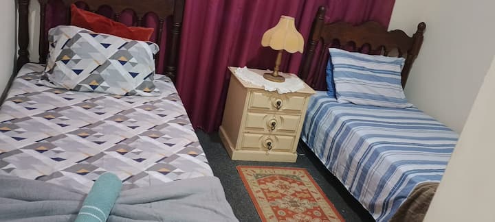 Kamer 2, twee eenpersoonsbedden en een plafondventilator.