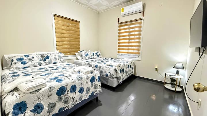 Acogedora habitación con dos camas matrimoniales, aire acondicionado, persianas blackout y un estilo fresco y floral. Ideal para familias o grupos que buscan comodidad y descanso tras disfrutar de la playa, a solo unos pasos del mar.