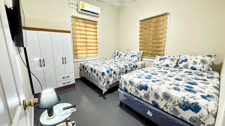 Espaciosa habitación con dos camas matrimoniales, aire acondicionado, clóset amplio, persianas tipo blackout y decoración floral. Ideal para descansar cómodamente tras un día de playa, perfecta para familias o grupos pequeños.

