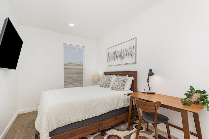 غرفة نوم حديثة وجذابة مع سرير بحجم وسط مريح، وتلفزيون 55بوصة، ومكتب دراسة مخصص، وخزانة ملابس واسعة - مصممة بعناية للاسترخاء والعمل والنوم لما يصل إلى ضيفين في راحة.