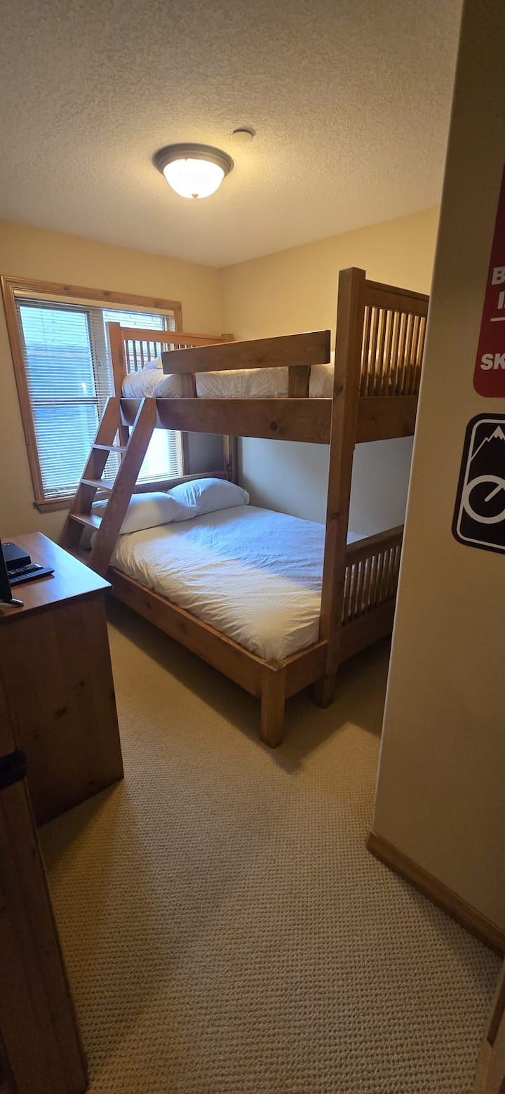 Habitación con literas con una cama doble en la parte inferior, una cama doble en la parte superior y un televisor inteligente.