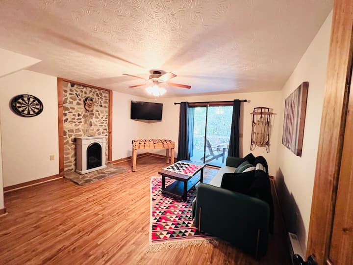 Basement living room with gas fireplace, patio access, games, and a pull-out futon—perfect for extra guests or cozy nights in.