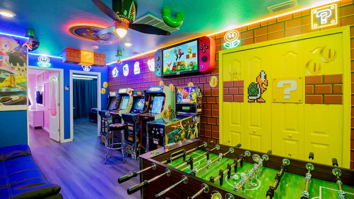 Uživajte u uzbudljivoj igraonici Super Mario! Ovaj prostor sadrži automate za igre, stol za nogomet, tematske slike na zidu, neonska svjetla, veliki televizor, zabavne ukrase i živahnu atmosferu za igranje igara, što ga čini savršenim za avanturu u Gljivnoj Kraljevini uz zabavu
