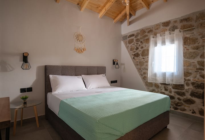 Manželská posteľ s kvalitnou posteľnou bielizňou a prírodným kameňom, ktorý dodáva charakter a tradičnú krásu.