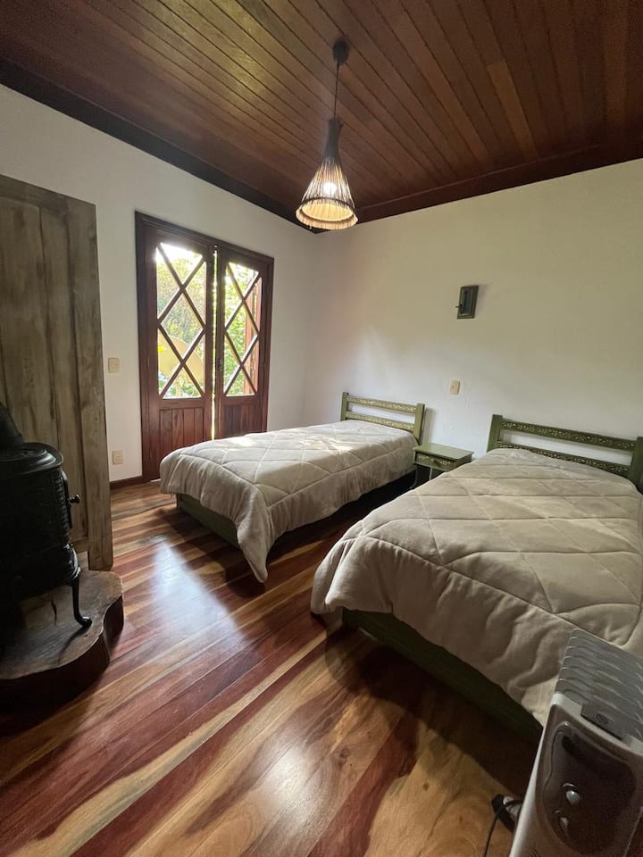 Habitación con dos camas individuales y una tercera opcional (una de ellas es bicama). Se puede volver a la cama doble. Calefator para los días fríos y puerta del balcón con salida al verde del jardín