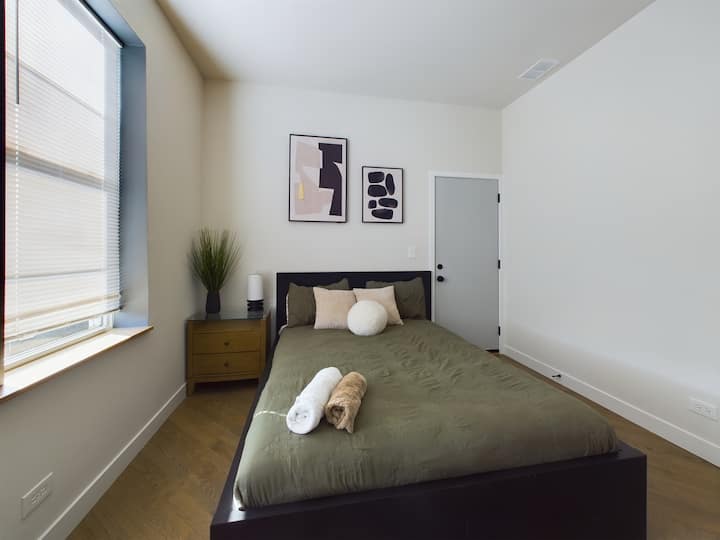 חדר שינה 1 מציע מיטת קווין סייז עם מצעים נקיים ואור טבעי רך מהחלון. עיצוב מודרני ואווירה מרגיעה הופכים אותו למקום המושלם לנוח ולמלא מצברים.