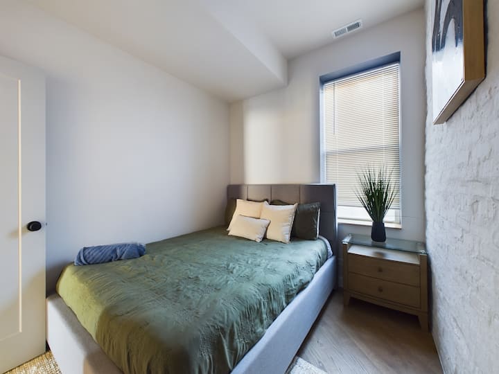 חדר שינה 2 מציע מיטת קווין סייז עם מצעים רכים, עם קיר לבנים חשוף לקסם נוסף. אור טבעי ועיצוב פשוט יוצרים מרחב נעים ומזמין להירגע בו.