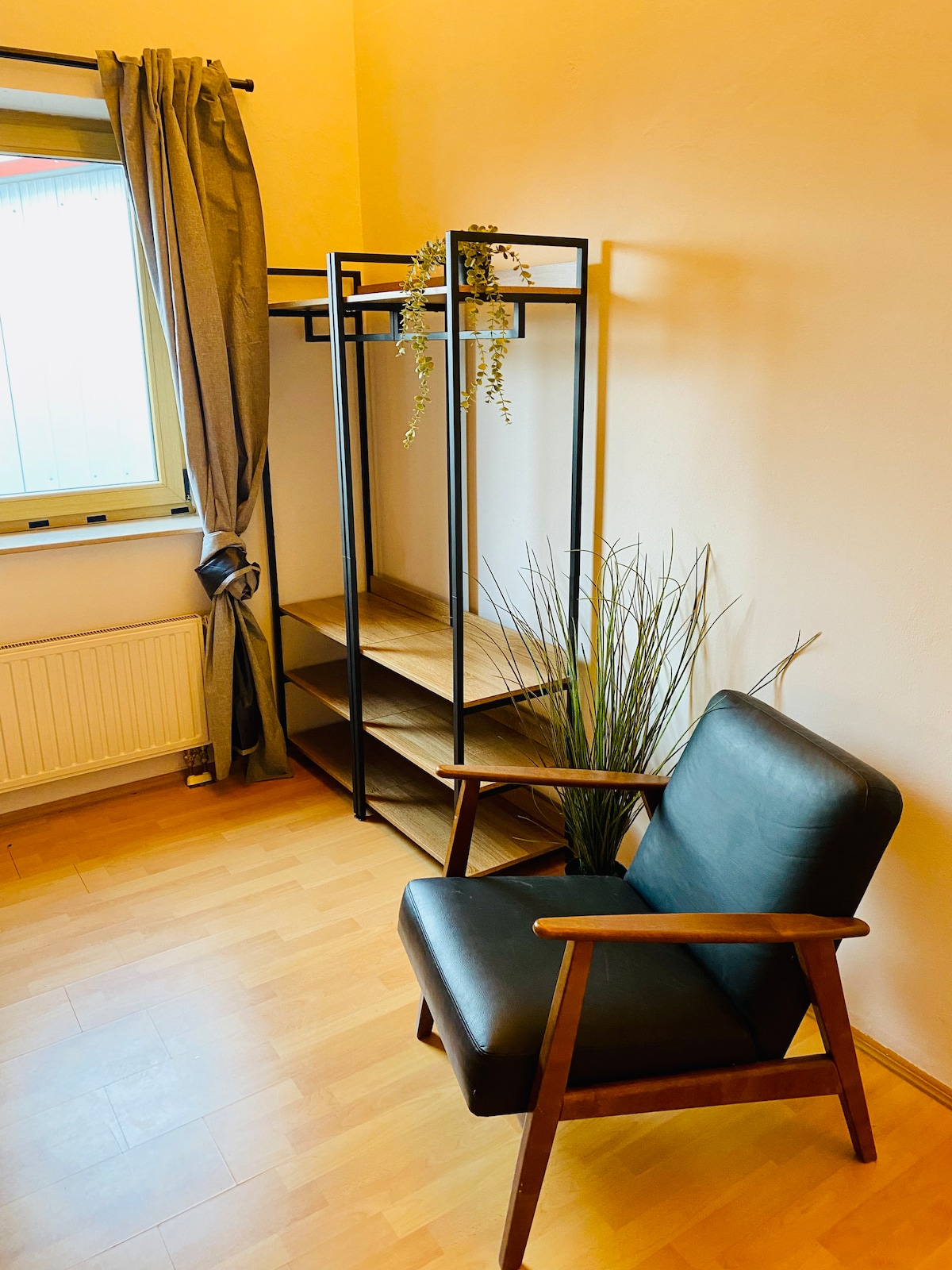 Dy gardëroba të hapura janë të disponueshme për rroba, një kolltuk i zi për t 'u ulur ose si raft rrobash. Dritarja mund të errësohet me grila, perdet gri janë aty sepse duket më bukur:)