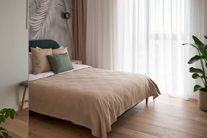 Het comfortabele tweepersoonsbed is het middelpunt van de slaapkamer, uitgerust met een kwaliteitsmatras en zacht beddengoed dat zorgt voor een goede nachtrust. Het hoofdeinde van het gestoffeerde bed geeft de ruimte een verfijnd gevoel.