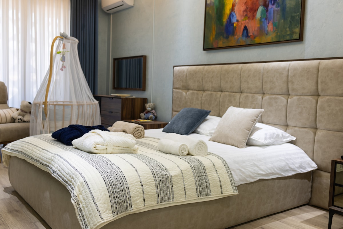 غرفة النوم 1 بمثابة غرفة رئيسية، مع سرير كبير الحجم، وخزانة ملابس واسعة، وحمام كامل مع حوض استحمام، ومغسلة، ومرحاض، ومنطقة غسيل، وتلفزيون ذكي مثبت على الحائط مع واي فاي عالي السرعة، وسرير أطفال قابل للإزالة لتناسب تفضيلات الحجز.