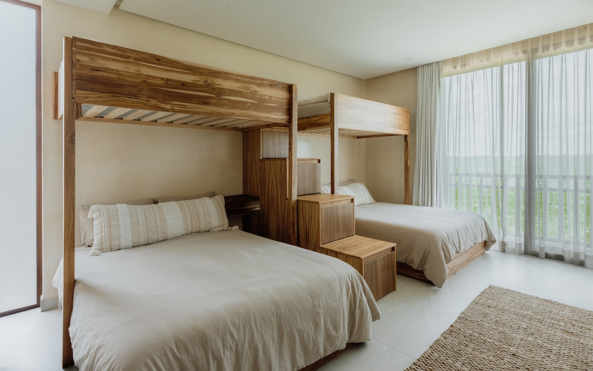 Two custom-built bunk beds take center stage in this room, sleeping up to six people. Enjoy balcony access and a convenient en-suite bathroom for added comfort.