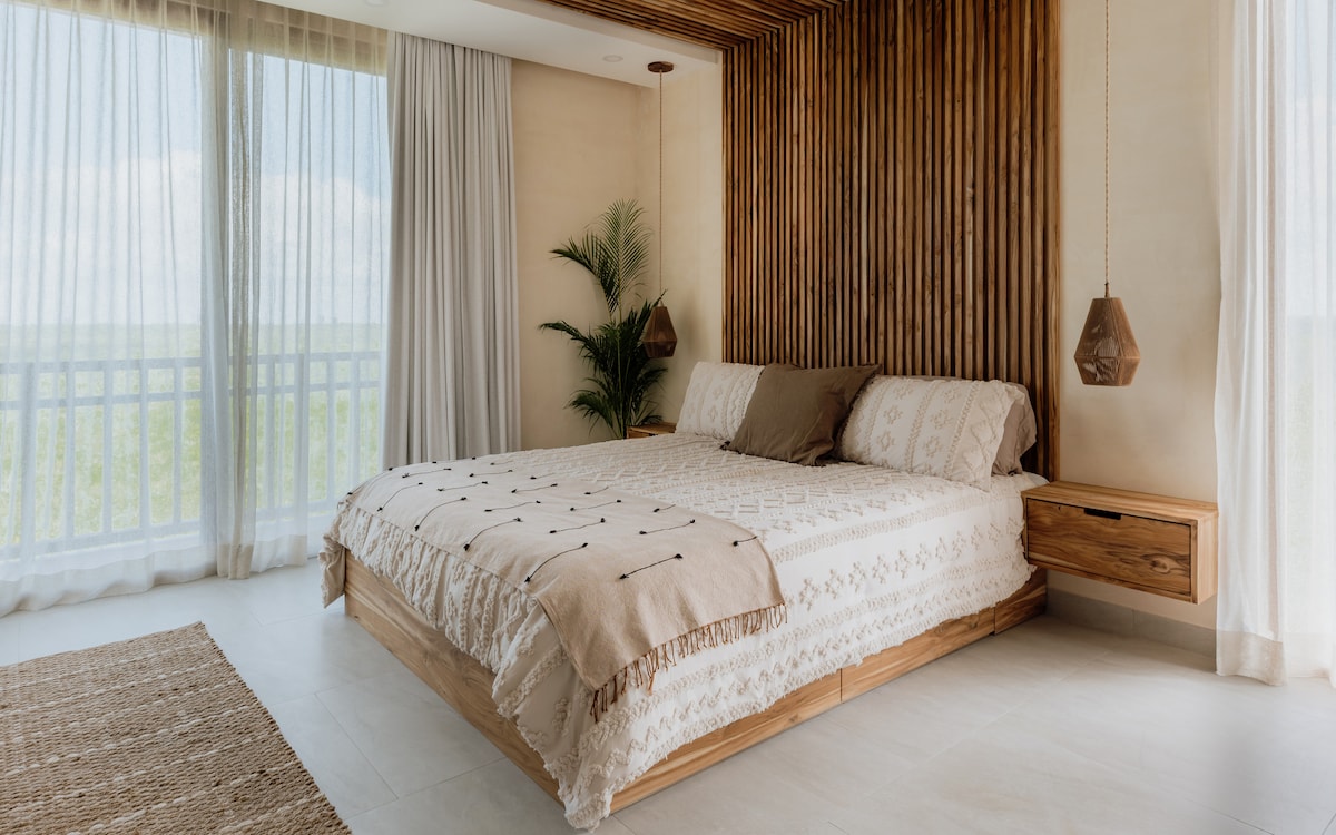 The second bedroom features a king-sized bed, a private balcony with views of the lush green jungle, an en-suite bathroom, and a TV for ultimate comfort.