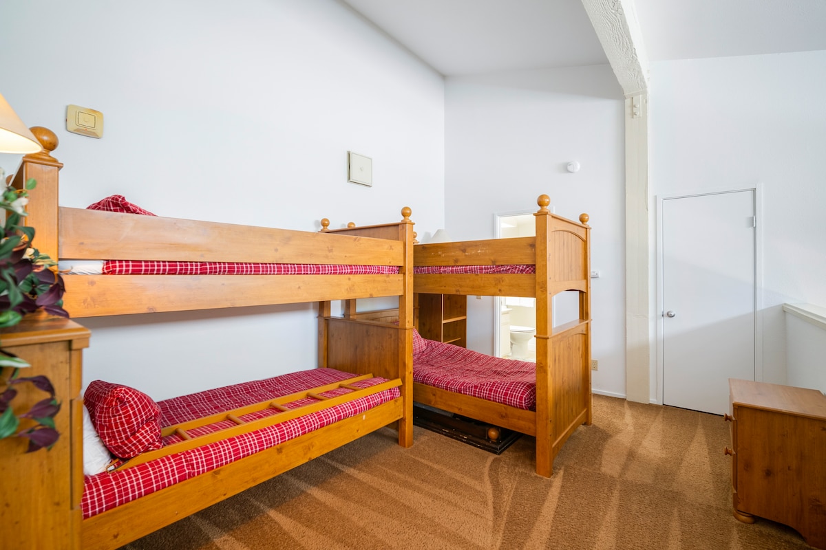 ห้องนอนใต้หลังคามีเพดานสูงที่น่าตื่นตาตื่นใจเตียงสองชั้นสองเตียงคู่และห้องน้ำส่วนตัวเหมาะสำหรับเด็กหรือคนหนุ่มสาวที่ต้องการพื้นที่ส่วนตัว