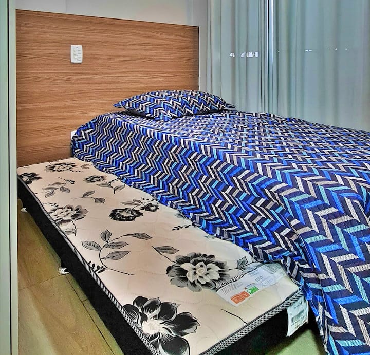 Bedroom 3 equipped with a single bed, auxiliary bed, air-conditioning, ceiling fan, smart TV with streaming, blackout curtains, place to store clothes and bedding.