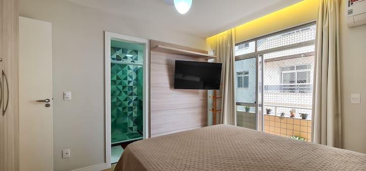 Bedroom 2 with private bathroom, queen-size bed, air-conditioning, ceiling fan, smart TV with streaming, blackout curtains, place to store clothes, bed linen and direct access to the balcony.