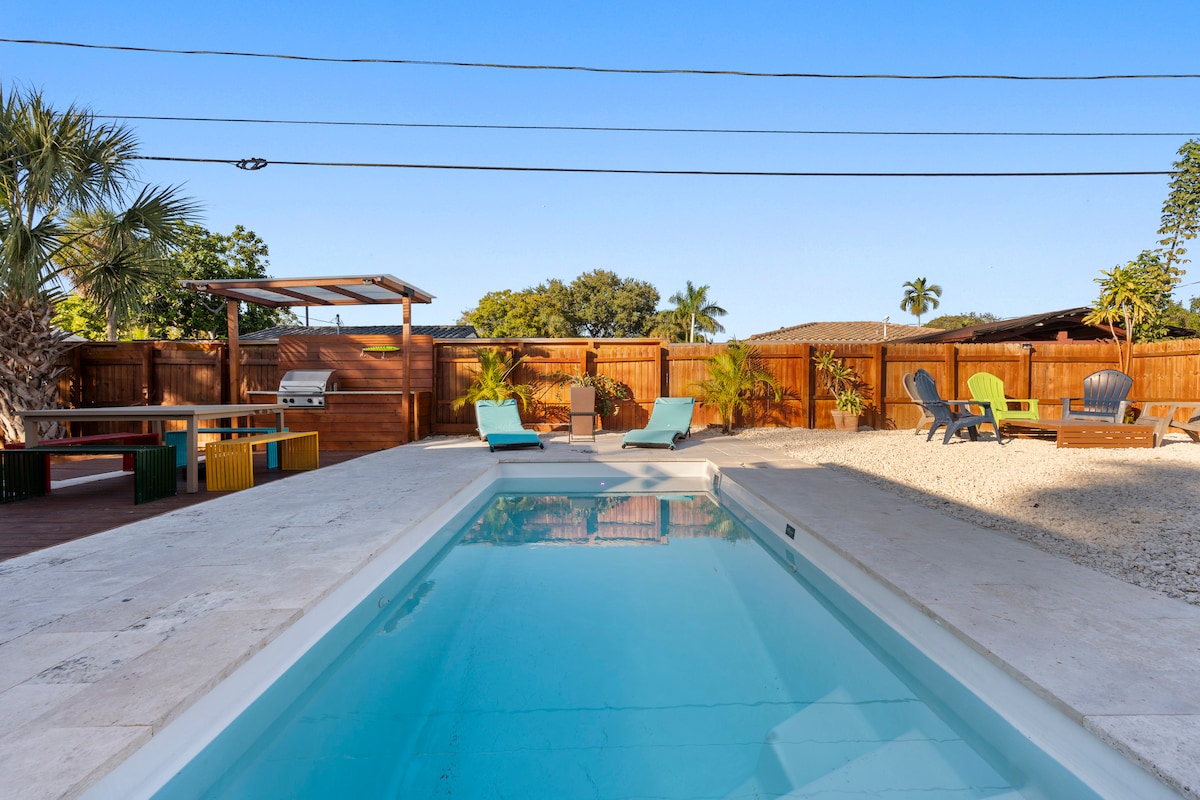 A private pool area is showcased, featuring a clear, inviting pool with lounge chairs positioned nearby. Sunbathing spaces are surrounded by landscaping elements and a wooden deck. A shaded seating area is visible in the background, adding to the outdoor ambiance.