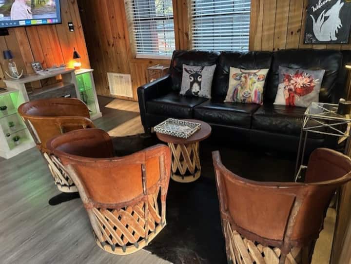 منطقة جلوس مريحة مع أثاث جلدي وتلفزيون ومكان نار جميل للتجمع حوله.