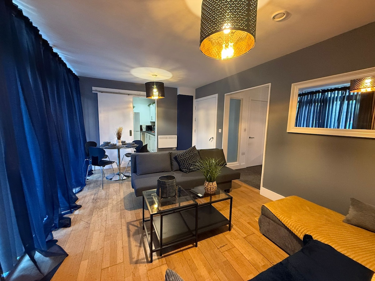 חלל פתוח מרווח עם טרקלין מעוצב, טלוויזיה עם מסך שטוח ושולחן אוכל, אידיאלי למנוחה או לעבודה מרחוק.