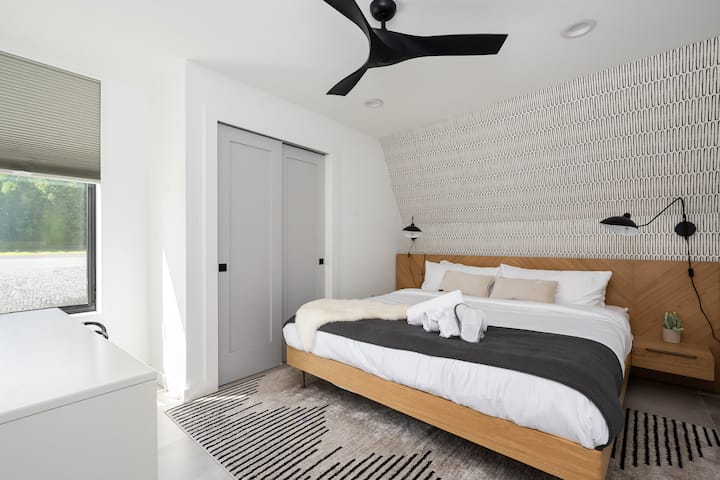 Spálňa na hlavnom poschodí s bezbariérovým prístupom, vyhrievanými podlahami a manželskou posteľou s luxusnou posteľnou bielizňou. Navrhnuté pre pohodlie so zatemňovacími žalúziami a stropným ventilátorom.