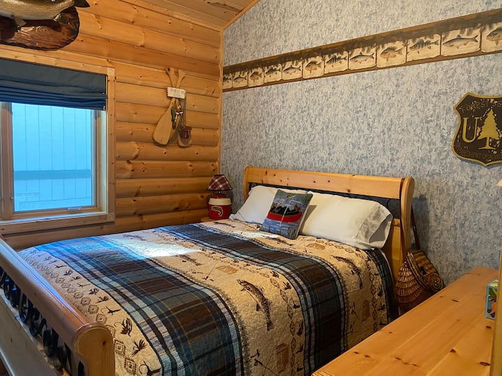 Visslaapkamer met queensize bed, dressoir en aan de muur gemonteerde smart-tv