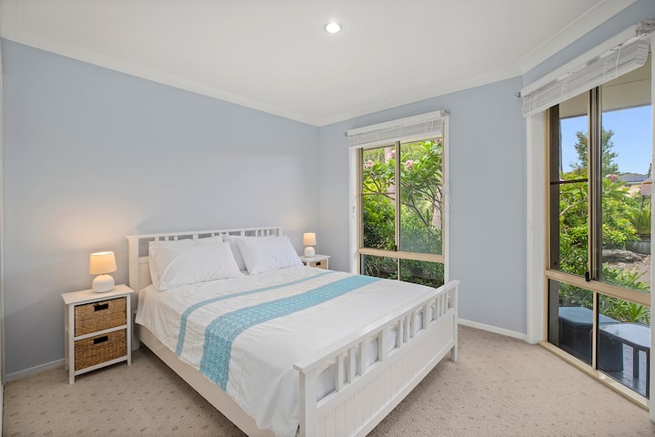 Bedroom 2 is spacious and filled with natural light from large windows, creating a bright, airy feel. The room is simple yet inviting, with soft neutral tones, offering a peaceful retreat perfect for relaxation and slumber.