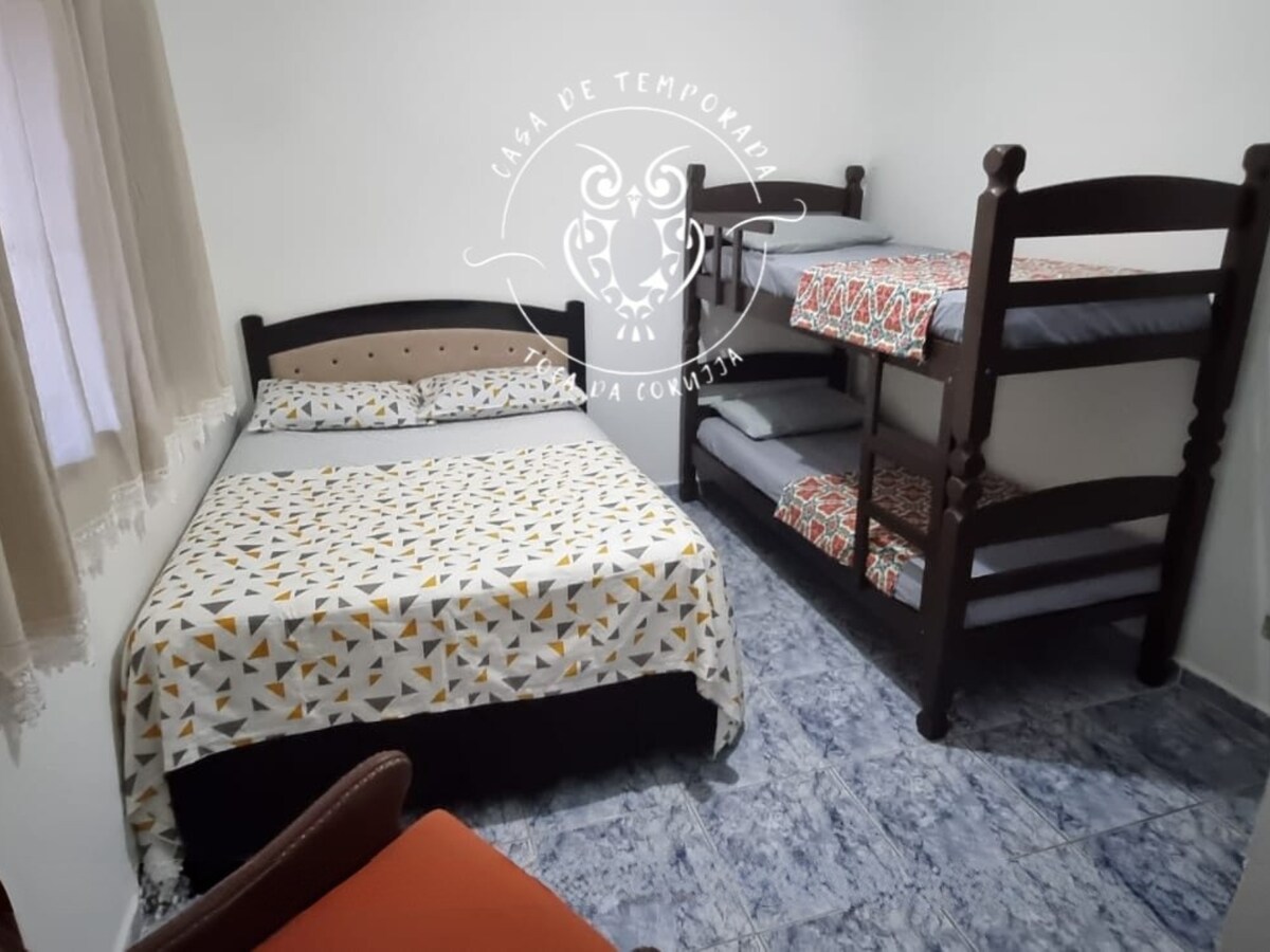 Chumba chenye kitanda cha watu wawili, kiti cha mikono na kitanda cha ghorofa, kinakaribisha watu 4 kwa starehe.