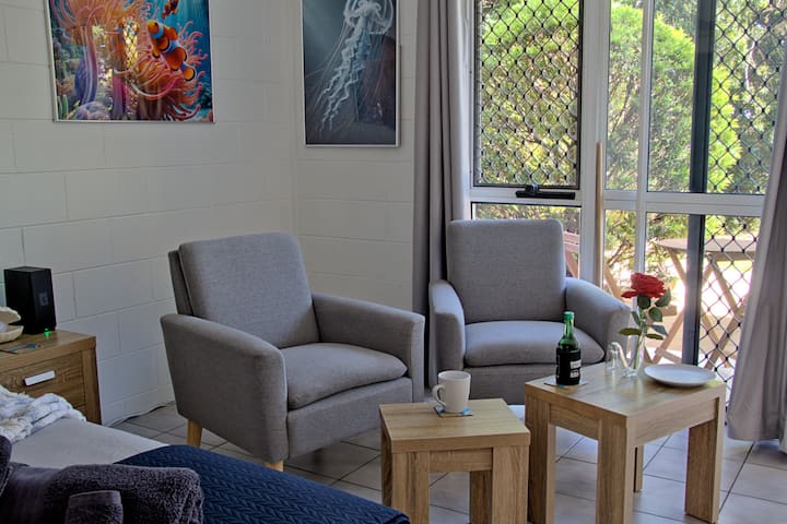 Relax and unwind in our cozy sitting area, complete with drinks for a welcoming touch. Enjoy the vibrant Great Barrier Reef artwork and a peek at the serene outdoor patio—perfect for a tranquil escape.