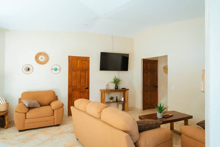 Unwind in our cozy living room, featuring comfortable sofa seating for five, a coffee table, and a large smart TV—perfect for relaxing or enjoying your favorite shows.