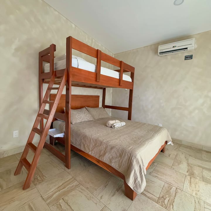 Bedroom 2 features a queen-size mattress on the bottom (sleeps 2) and a twin-size mattress on the top bunk (sleeps 1). Enjoy direct access to the front yard through the patio sliding door, and stay comfortable with your own independent AC system