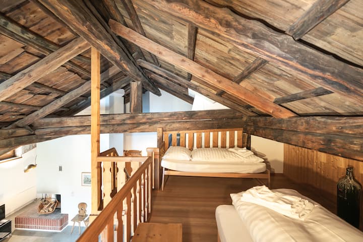 Ugodna spavaća galija ispod povijesnih krovnih greda – s dva jednostruka kreveta i pogledom na dnevni boravak. Savršeno za djecu ili prijatelje.

