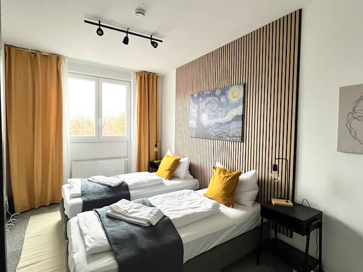 Chumba cha kulala cha watu 2 kilicho na kabati na viti pamoja na televisheni mahiri. Vitanda vinaweza kusukumwa kando au kusukumwa pamoja.