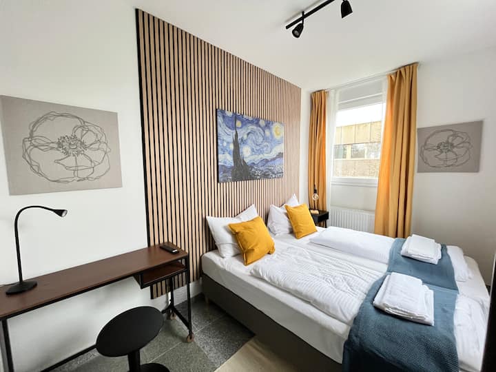 Chumba cha kulala cha watu 2 kilicho na kabati na viti pamoja na televisheni mahiri. Vitanda vinaweza kusukumwa kando au kusukumwa pamoja.