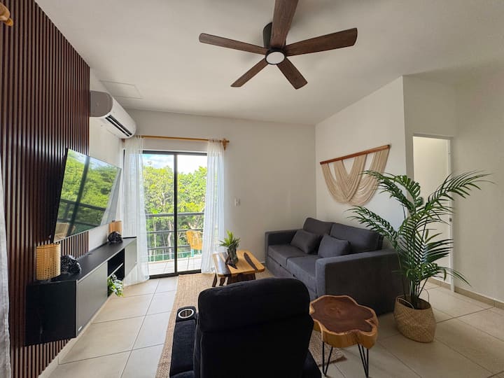 Მისაღები ოთახი კომფორტული დივნით, მოსასვენებელი სკამებით, ხის ნამდვილი მაგიდით და ჯუნგლების ხედებით